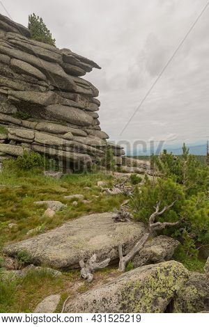 Large Kurum Stones Lie In The Forest In The Mountains, Stones Covered With Moss, Against The Backgro