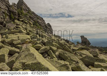 Large Kurum Stones Lie In The Forest In The Mountains, Stones Covered With Moss, Against The Backgro
