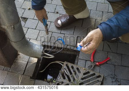 A Master Fixing Electric Wire Outside Of Downspout With Adhesive Tape, Outdoor Closeup