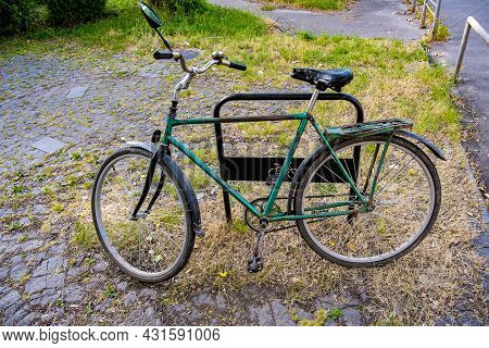 An Old Rusty Bicycle Is Parked In The Bicycle Parking Lot.