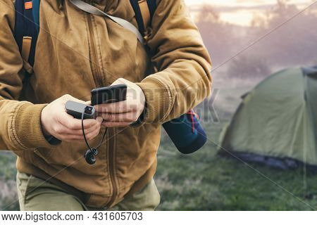 Man Holds A Smartphone In His Hands And Charges It With A Power Bank Against The Backdrop Of A Touri
