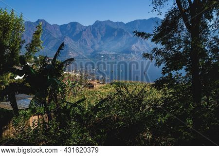 Tropical Plants And Local Husts Along The Coast Of Lake Atitlan With View To The Volcanic Mountain R