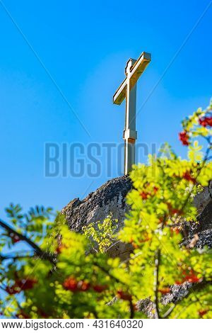 A Beautiful Gilded Peasant Orthodox Symbol Stands On The Top Of A Cliff, A Mountain, Glitters With R