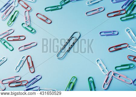 A Large Paper Clip Surrounded By Small Colored Paper Clips On A Blue Background