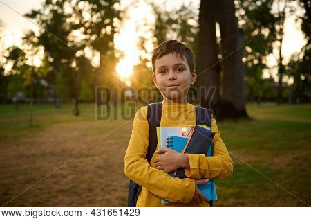 Confident Portrait Of A Happy Handsome School Child Boy 9 Years Old With School Bag Holding Workbook