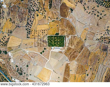 Aerial view on a green football field during drought on sifnos island, Greece 