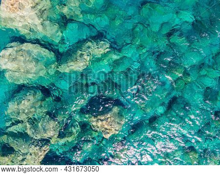 Azure water texture, transparent sea surface with a rocky bottom. Aerial view, Chora, agian Anna, Amorgos, natural blue background