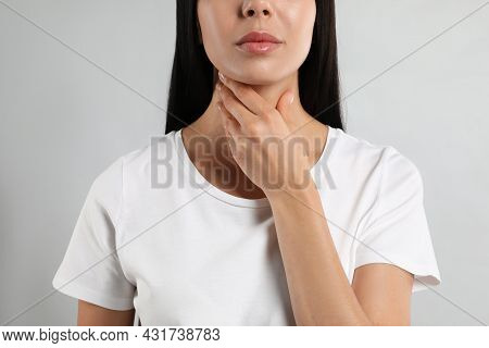 Young Woman Doing Thyroid Self Examination On Light Background, Closeup