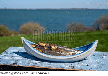 Smoked Sprattus Or Sprats Sea Fish Served Outdoor With View On Blue Sea Water