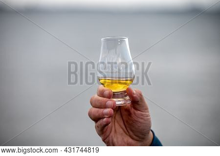 Hand With Dram Of Single Malt Scotch Whisky On Seashore In Scotland