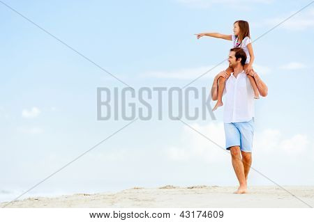 Pai e filha apontando e olhando para o oceano juntos