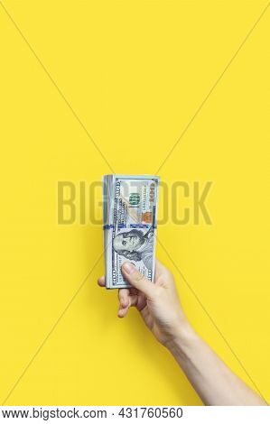 Hand Holding A Big Stack Of Banknotes Isolated On Yellowbackground. Wealth Or Loan Concept. Vertical