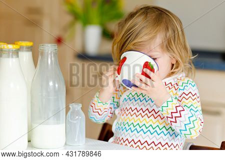 Adorable Toddler Girl Drinking Cow Milk For Breakfast. Cute Baby Daughter With Lots Of Bottles. Heal