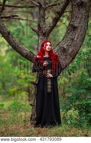 Courageous Young Lady With Long Red Hair In The Image Of A Fabulous Historical Character Of A Witch 