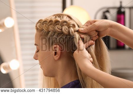 Professional Stylist Braiding Client's Hair In Salon