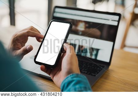 Top View Close Up Man Hands Holding Blank Screen Mock Up Mobile Phone And Using Laptop Computer. Emp