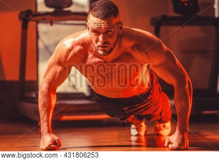 Slim Man Doing Some Push Ups A The Gym. Muscular Man Doing Push-ups On One Hand Against Gym Backgrou