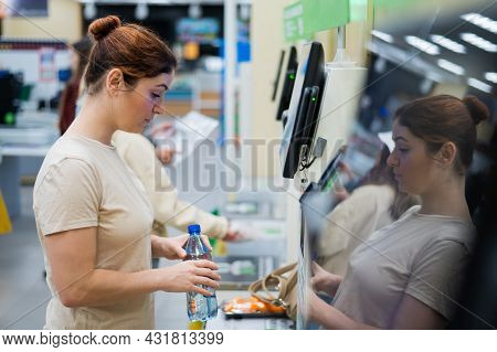 A Frustrated Woman Uses A Self-checkout Counter. The Girl Does Not Understand How To Independently B