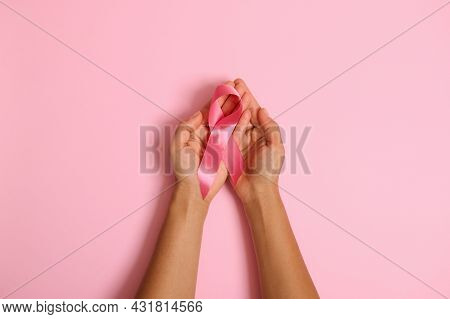 Top View Of Hands Holding Pink Ribbon On Pink Background, Breast Cancer Awareness, October Pink Day,