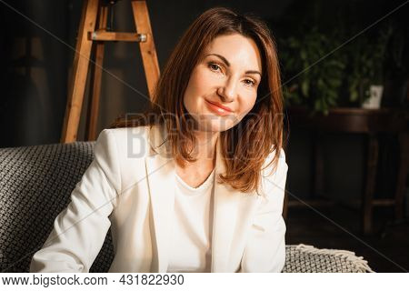 Portrait Of A Beautiful Middle-aged Woman With Straight Shoulder-length Hair. A Woman Sits In A Chai