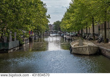 Amsterdam, Netherlands - August 15, 2021: Narrow Canal Between Rows Of Green Tree Foliage With Ponto