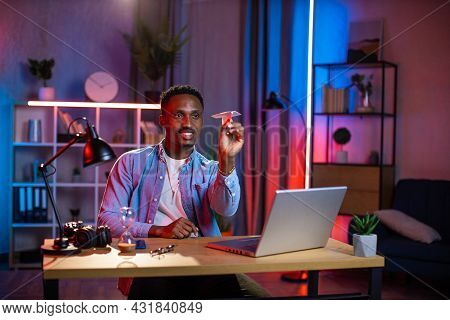 Happy Young Man In Casual Wear Throwing Paper Airplane While Taking Break During Remote Work On Lapt