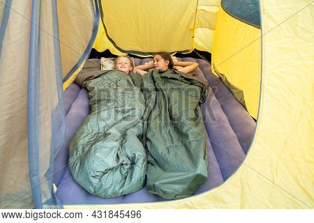 Two Happy Young Girls Lying In Sleeping Bags In A Tent