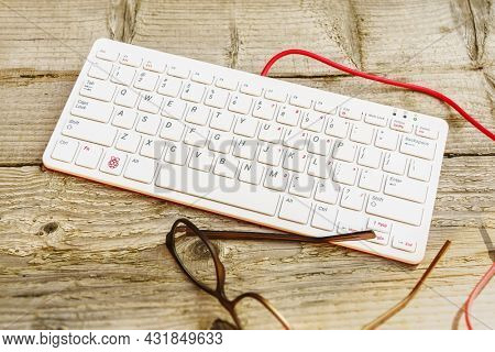 Ihringen, Baden Wuerttemberg, Germany - September 3rd, 2021: Raspberry Pi 400 Keyboard outdoor on a wooden table with glasses.