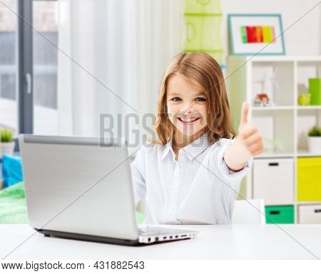 education, school and technology concept - happy smiling student girl with laptop computer learning online and showing thumbs up over home room background