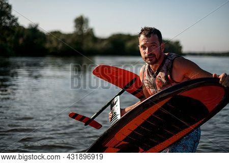 Adult Athletic Wet Man Holding Bright Foil Board In His Hands