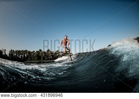 Great View Of Adult Man Riding On The Wave With Hydrofoil Foilboard On Background Of Blue Sky