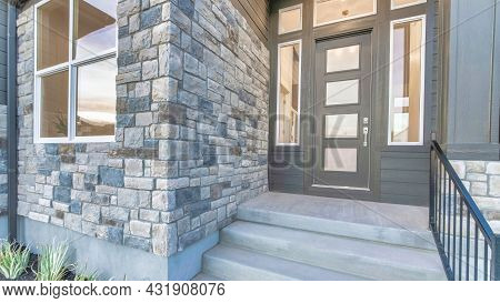 Pano Home Facade With Stone Brick Wall And Gray Front Door With Frosted Glass Panels