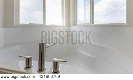 Pano Corner Bathtub In A Bathroom With Widespread Faucet Against The Windows