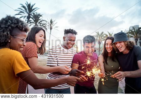 Group Of Friends Smiling And Having A Good Time Around Some Sparklers. Mixed Race Youngsters Enjoy S