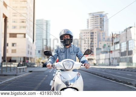 Middle Shot Of A Young Motorcyclist Stopped At A Traffic Light In Barcelona. The Man Rides Through T