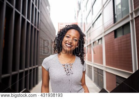 Attractive Latin Woman Looking At Camera Through City Streets Outdoors Near Large Office Building In