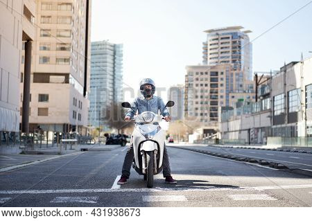 Wide Shot Of A Young Motorcyclist Stopped At A Traffic Light In Barcelona. The Man Riding His Scoote