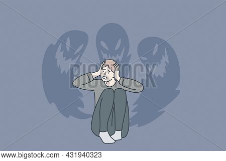 Phobias And Inner Fears Concept. Young Stressed Man Sitting Touching Head Feeling Bad With Ghosts At