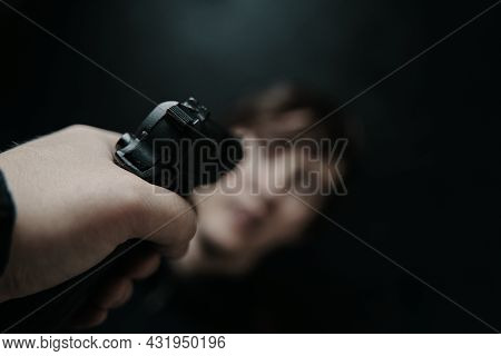 First Person View Of Gun Aimed At Young Man On Black Background. Firearm In Mans Hand. Pov Of Aiming