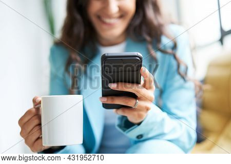 Close-up Of Hands Of Unrecognizable Business Woman Drinking Coffee Sitting On A Sofa While Using A S
