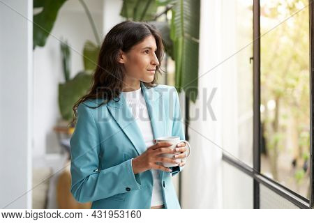 Young Business Woman Satisfied With A Job Well Done Relaxing With Her Morning Coffee Or Tea, Looking