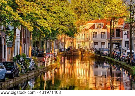 Delt canal with old houses and cars parked along on sunset. Delft, Netherlands