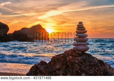 Concept of balance and harmony. Cairn stack of stones pebbles cairn on the beach coast of the sea in the nature on sunset. Meditative art of stone stacking