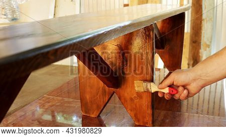 Applying Varnish On A Wooden Bench Standing On A Work Table In A Carpenter's Workshop, Varnishing A 