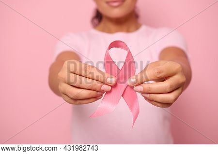 Cropped View Of A Young Woman In Pink T-shirt Holding A Pink Satin Ribbon Isolated On Colored Backgr
