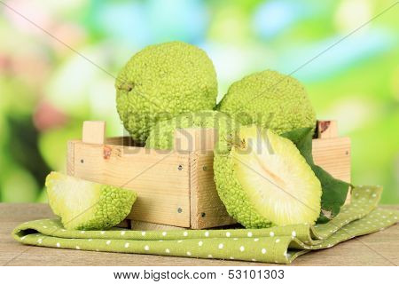 Osage Orange fruits (Maclura pomifera) in crate, on wooden table, on nature background