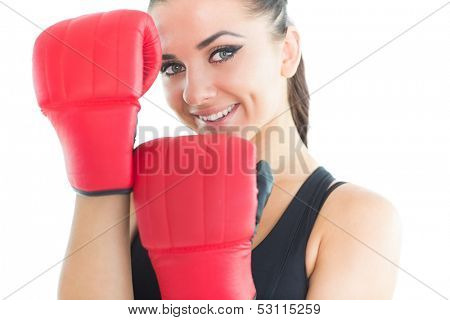 Attractive sporty woman smiling at camera wearing boxing gloves on white background