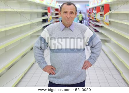 Anciano se encuentra entre los estantes vacíos en tienda