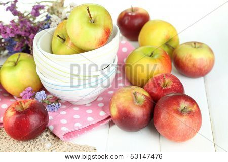 Juicy apples on plate on white wooden table