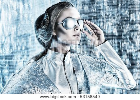 Beautiful young woman in silver latex costume and glasses with futuristic hairstyle and make-up. Sci-fi style.